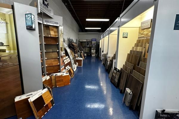 Storage hallway with blue floor, lined with shelves and stacked boxes on both sides