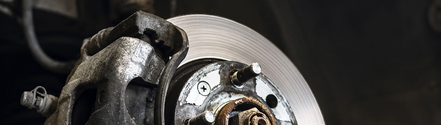 Close-up of a car brake rotor and caliper with a metallic wheel hub.