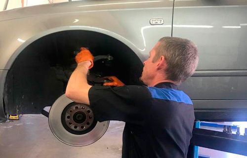 A man is working on the brake rotor of a car.