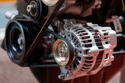 A close up of an alternator on a car engine.