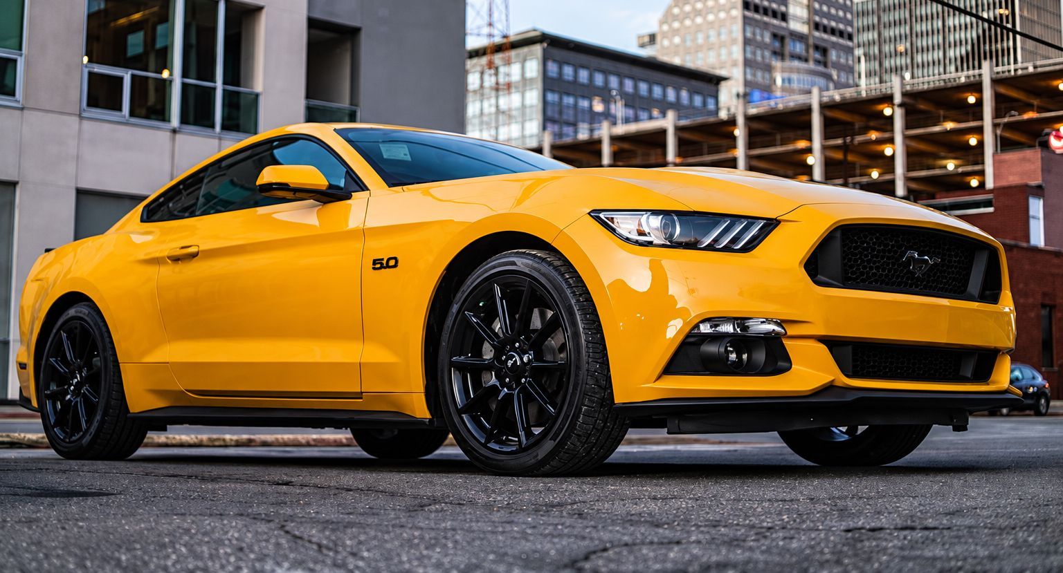 Yellow sports car parked on a city street in front of modern buildings