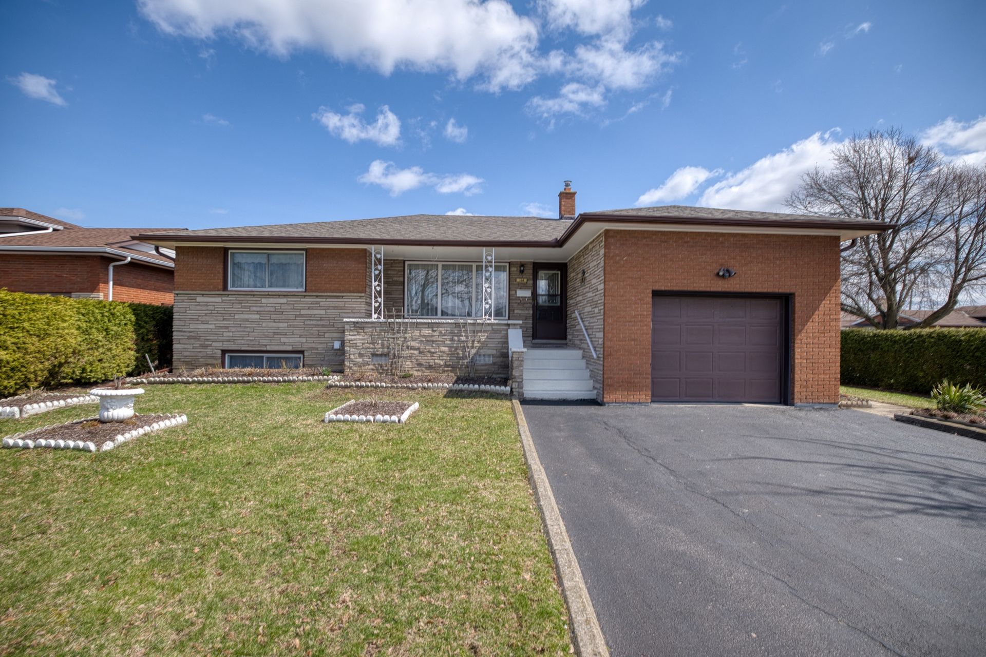 A detached brick and stone bungalow with a single-car garage.