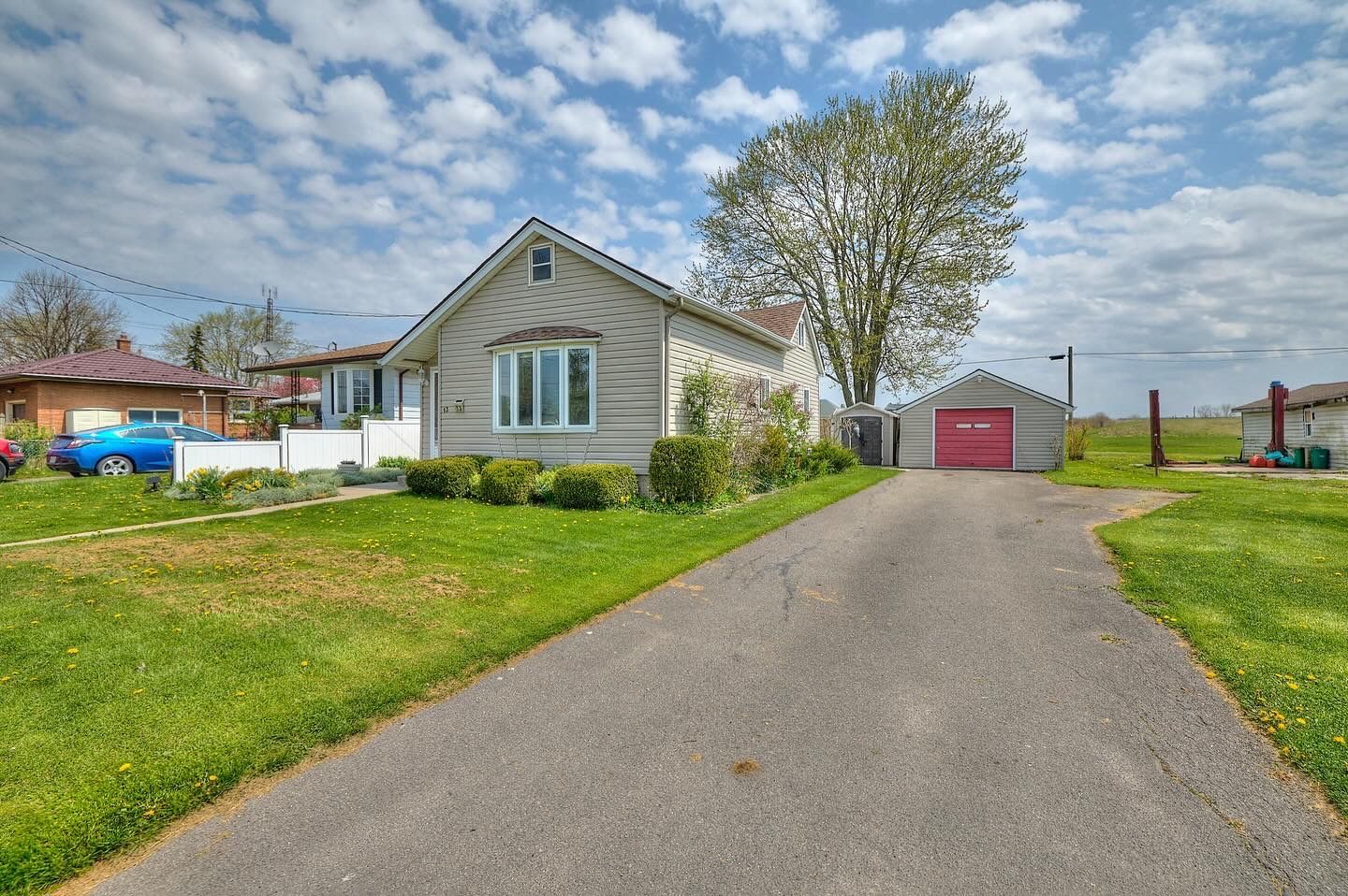 A detached bungalow with a detached red door garage.