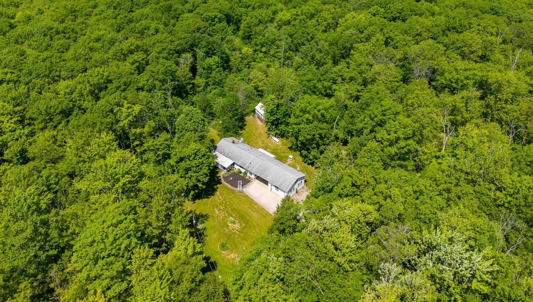 Aerial view of a secluded home surrounded by dense green trees.