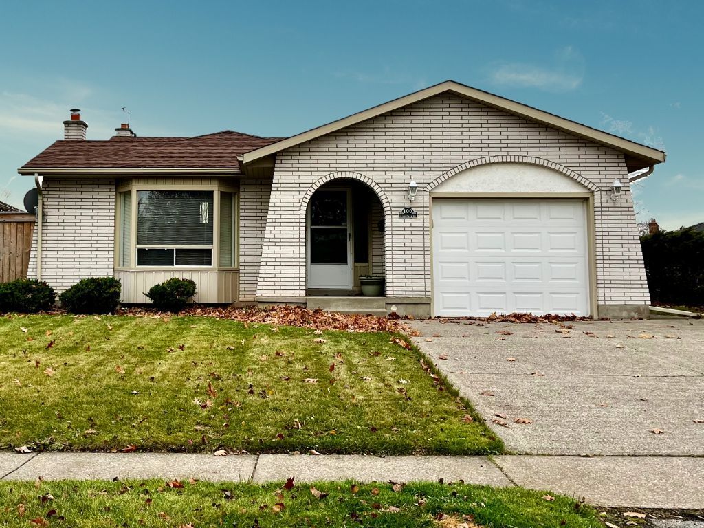 A white brick detached home with green grass and a blue sky.