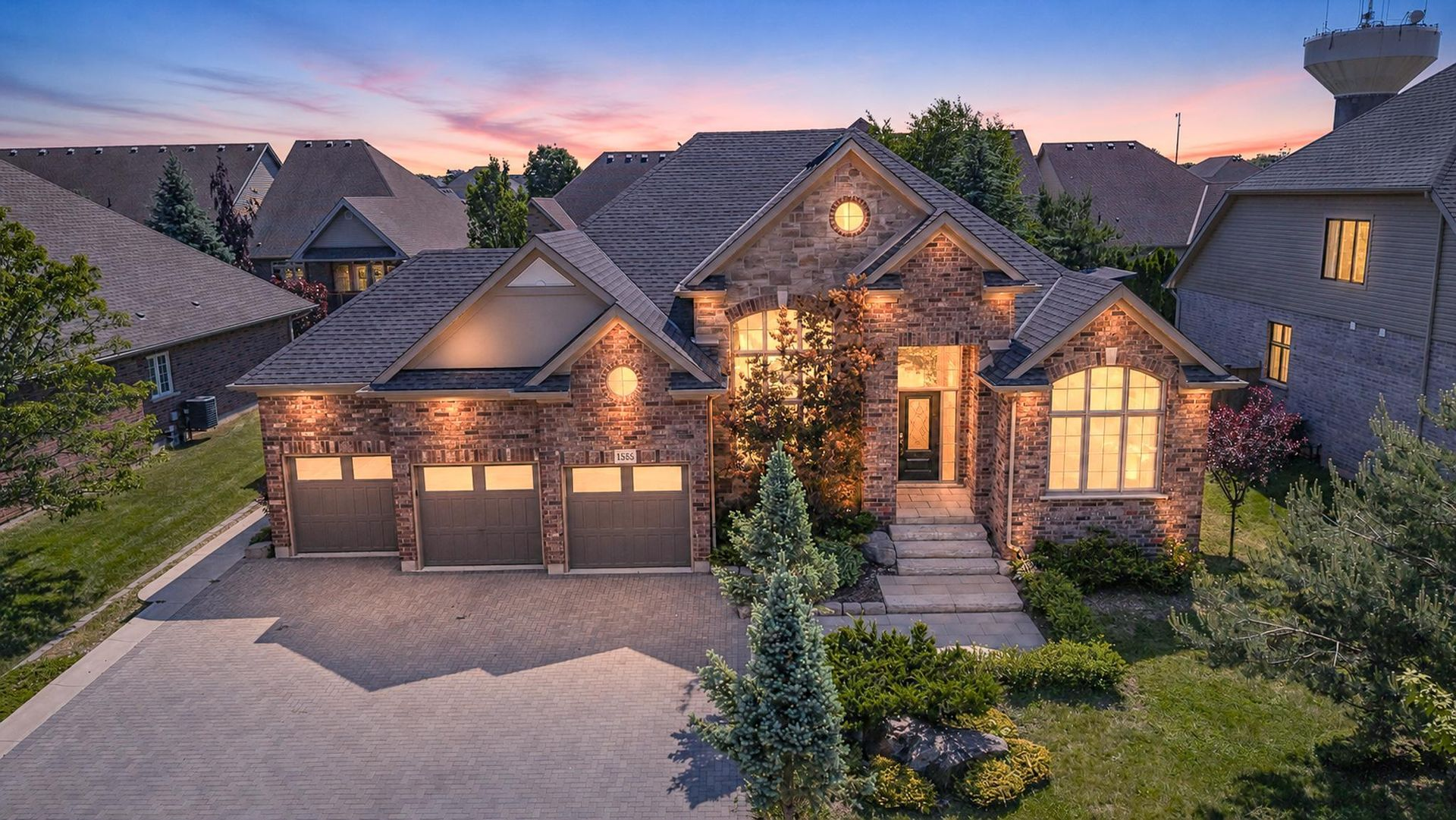 Twilight exterior view of a brick and stone bungalow with a triple-car garage.