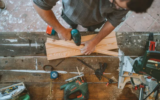 Aarons Repair and Remodel - A man is working on a piece of wood on a wooden table.
