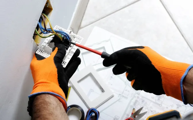 Aarons Repair and Remodel - An electrician is working on a light switch with a screwdriver.