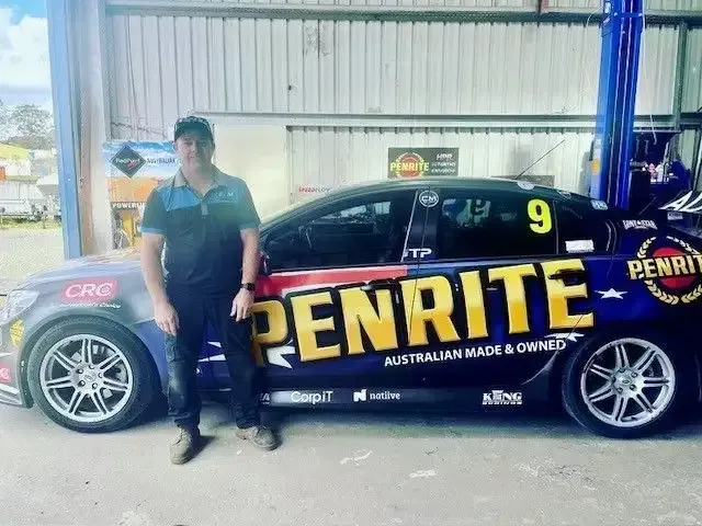 A Man is Standing in Front of a Penrite Race Car — East Coast Mechanic in Nambucca Heads, NSW