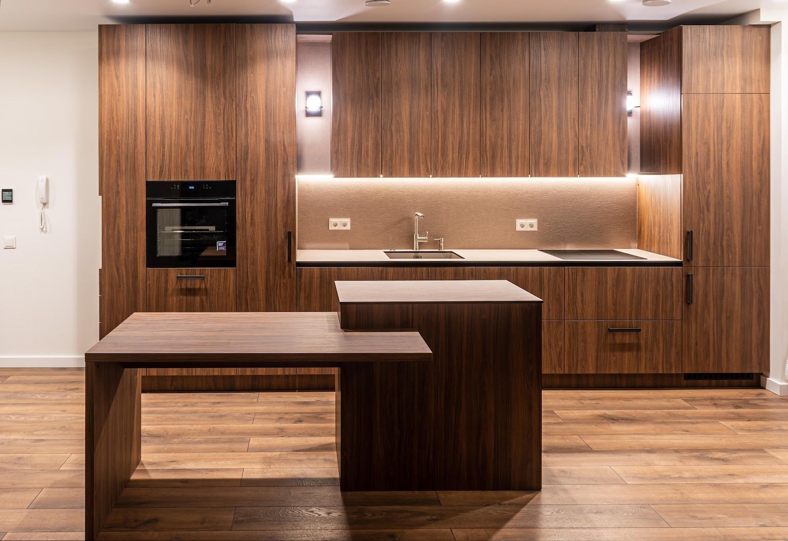 Modern kitchen with wood cabinetry, built-in oven, island, and wood-paneled walls