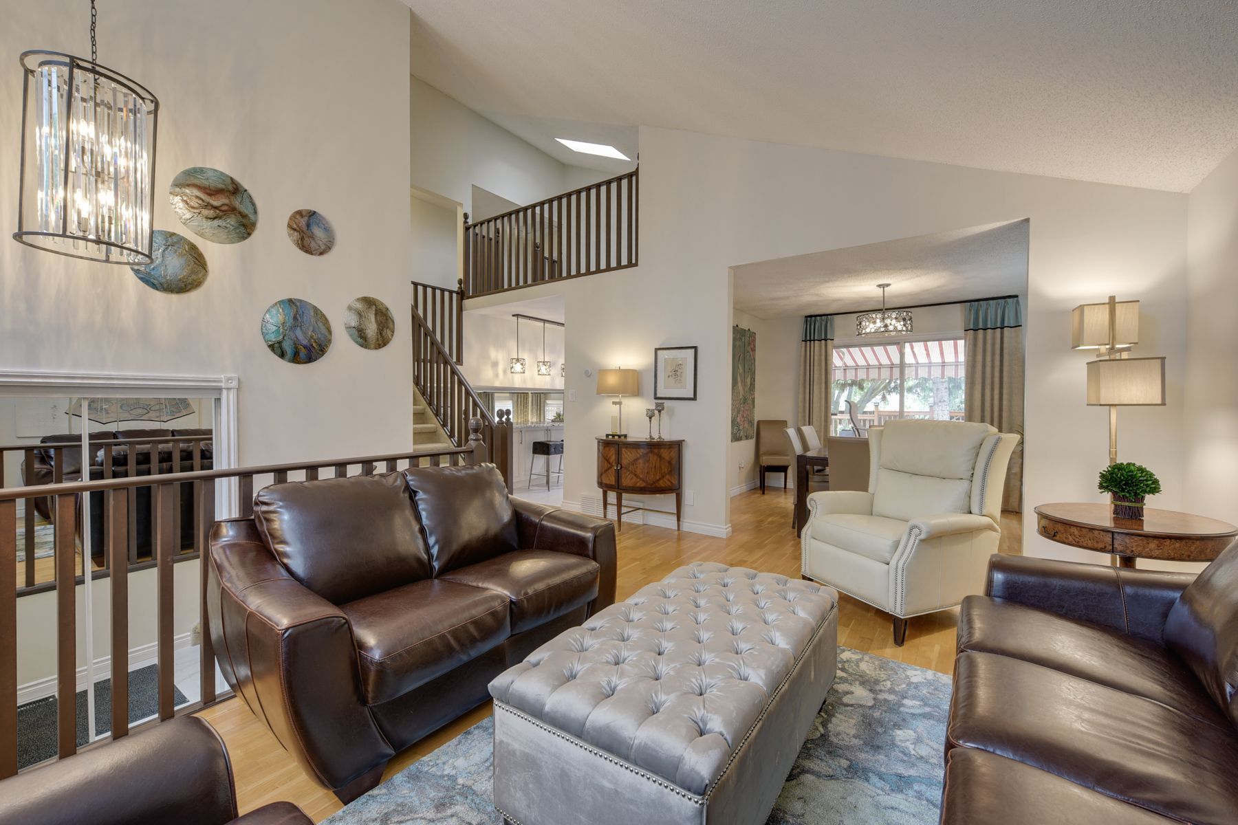 A living room with a couch , chairs , ottoman and chandelier.