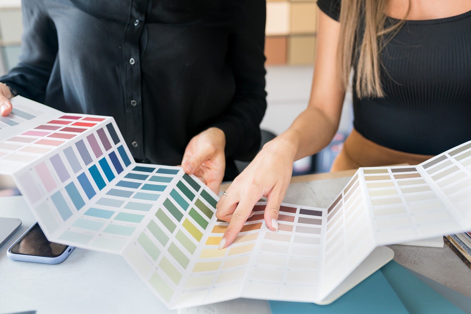 Two people reviewing printed color swatches and fabric samples at a design table