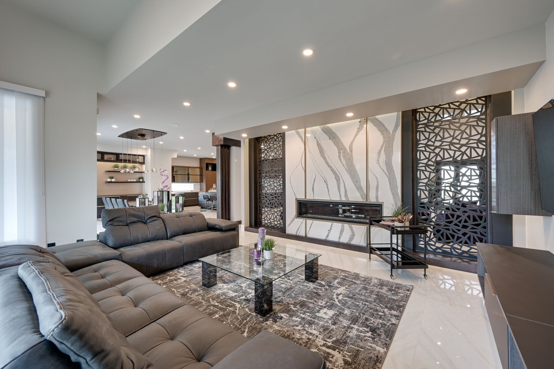 Modern living room with gray sofas, patterned rug, and decorative wall panels in a bright open space