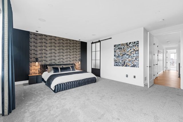 A bedroom with a large bed and a painting on the wall.