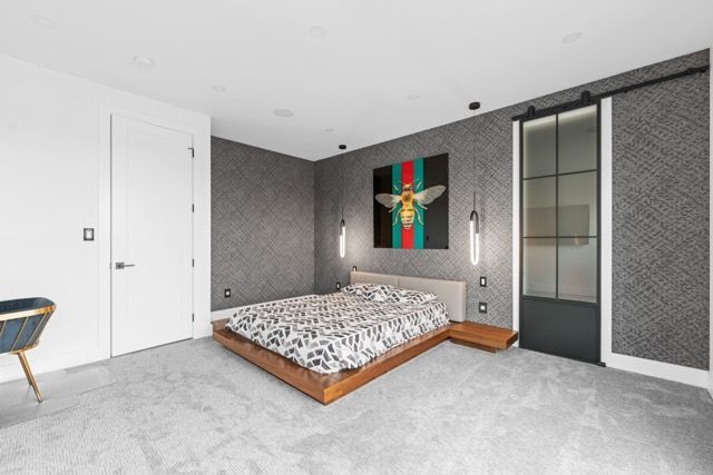 A bedroom with a bed and a painting of a bee on the wall.