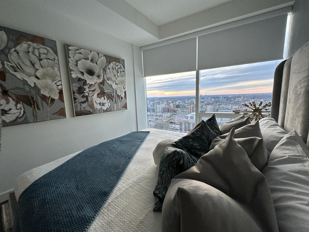 A bedroom with a large bed and a large window with a view of the city.