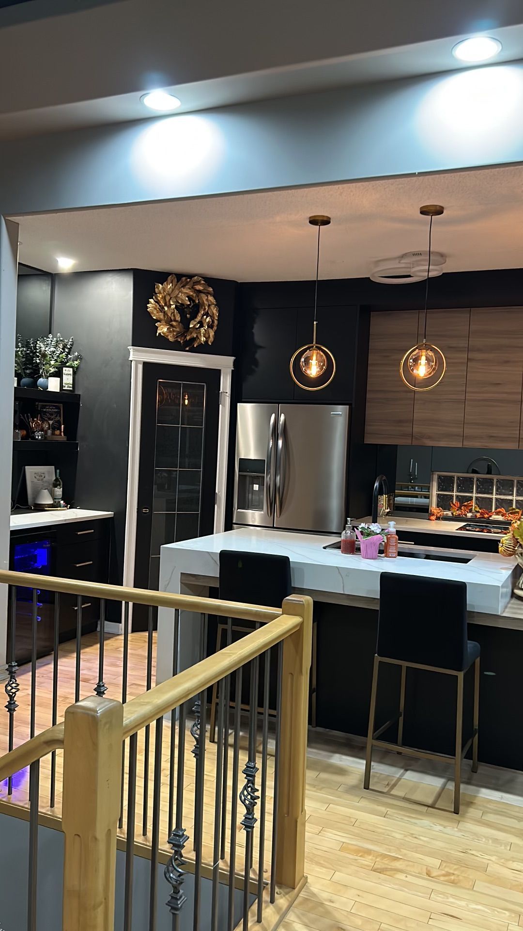 A kitchen with a stainless steel refrigerator , sink , and bar stools.