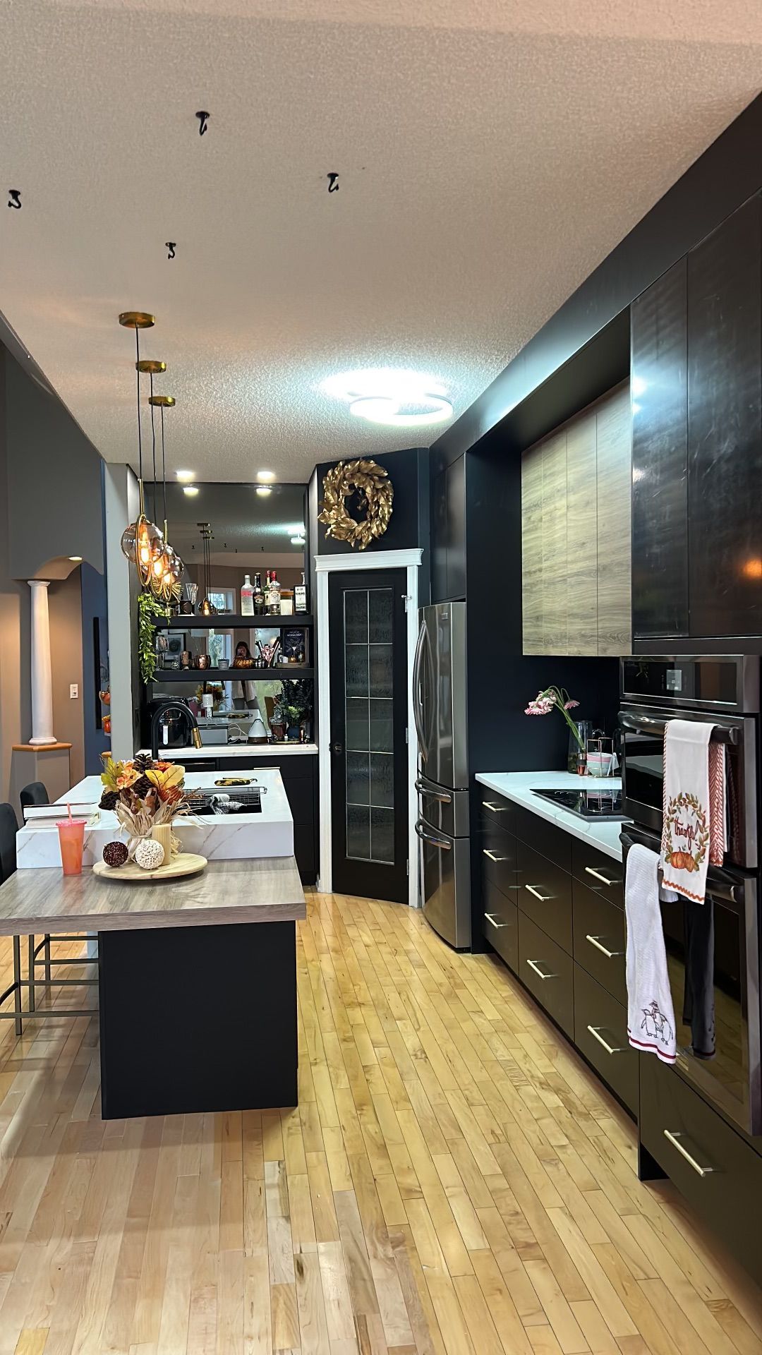 A kitchen with black cabinets and wooden floors and a large island in the middle.