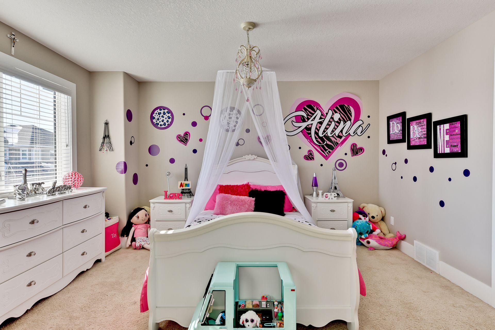 A girl 's bedroom with a canopy bed and a heart on the wall.