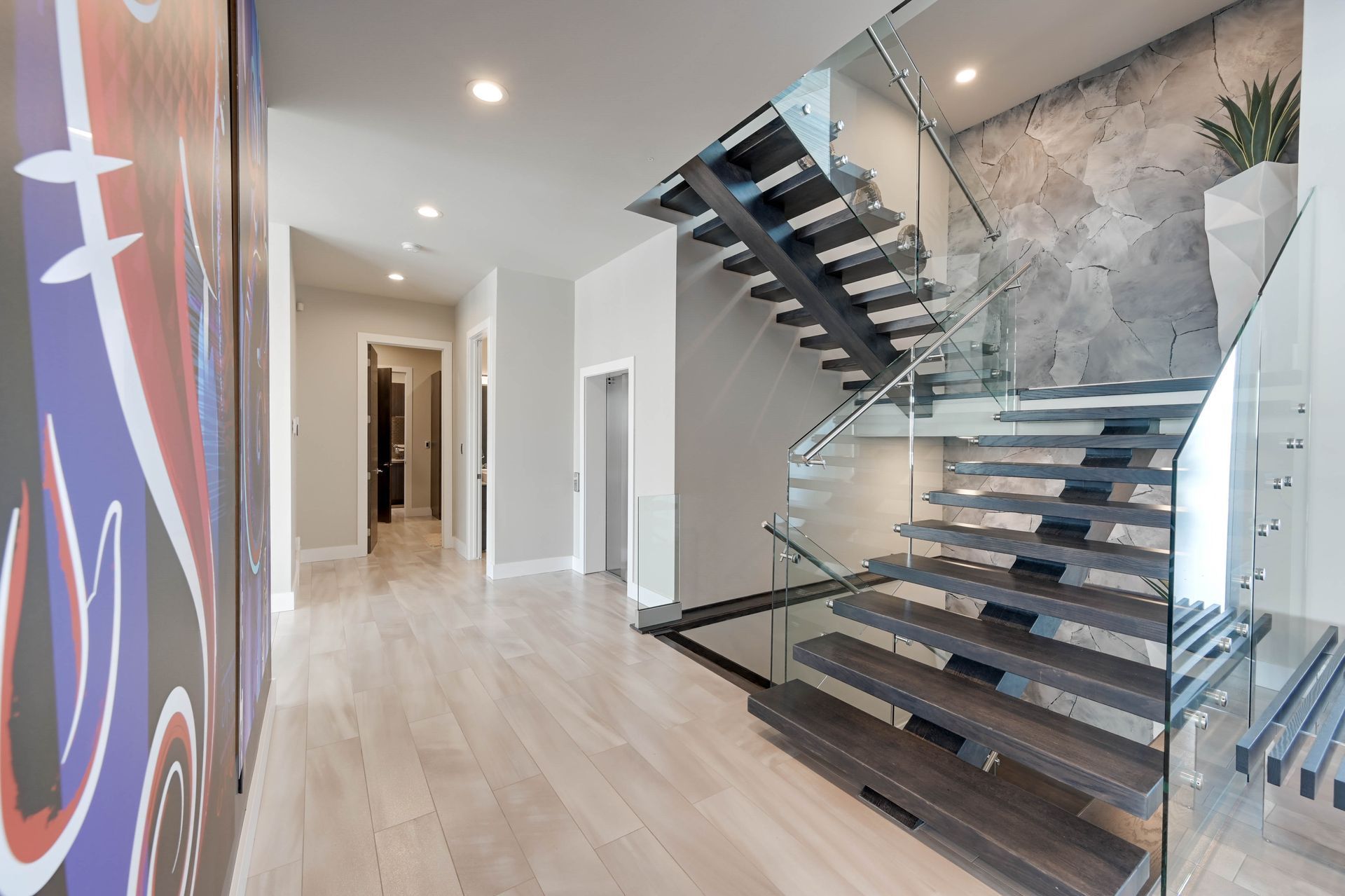 A modern staircase with a glass railing in a hallway.