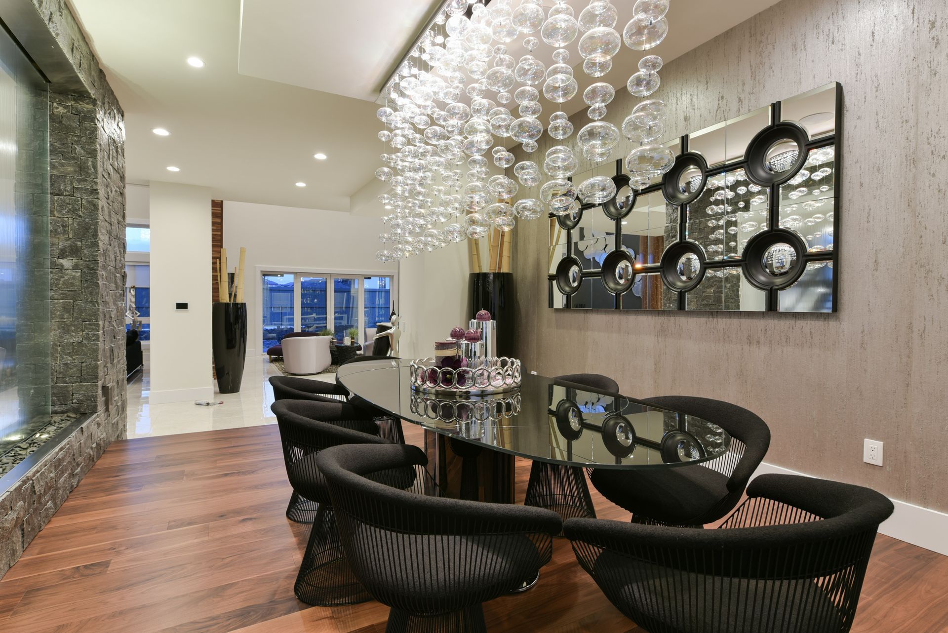 A dining room with a glass table and chairs and a chandelier hanging from the ceiling.
