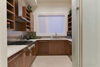 A kitchen with wooden cabinets , stainless steel appliances , and a large window.