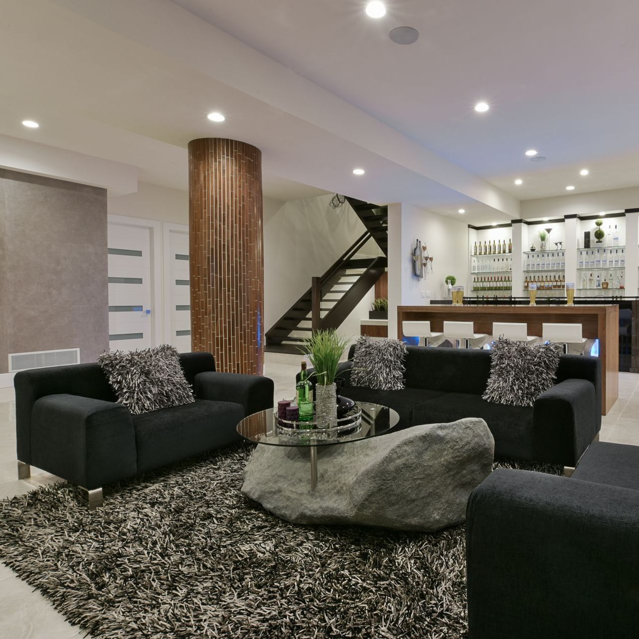A living room with two black couches and a rug