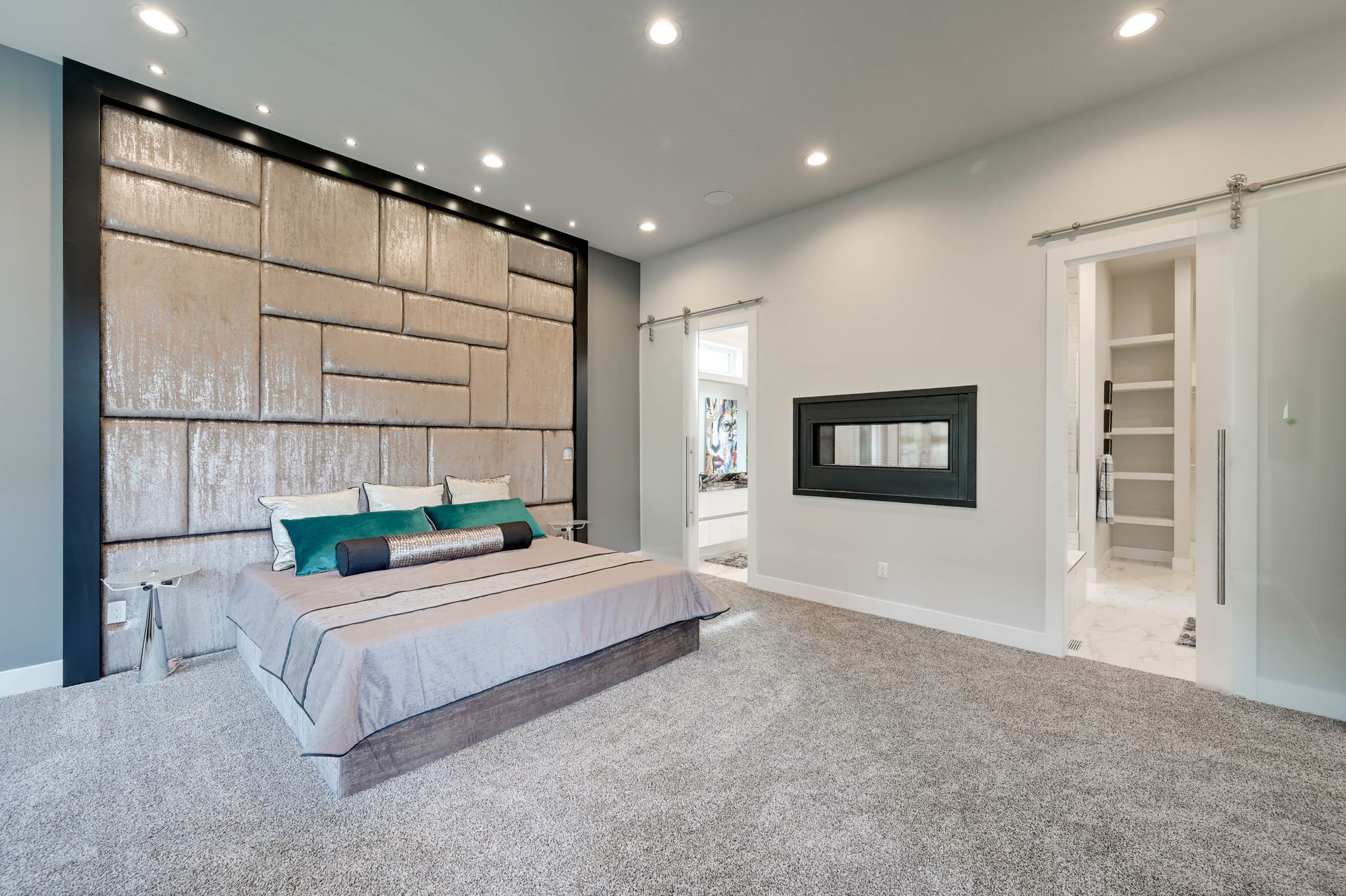 A bedroom with a large bed and a sliding barn door.