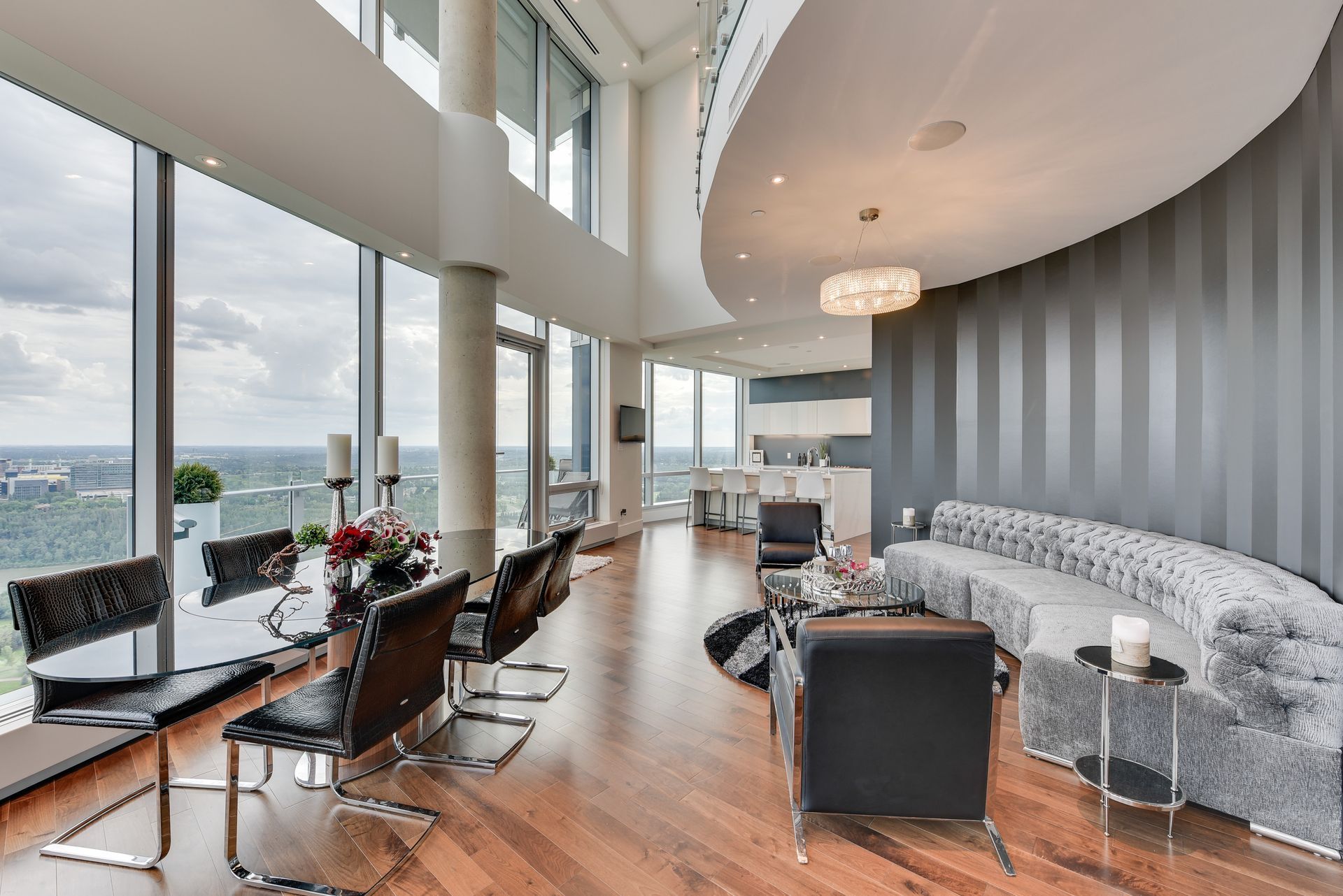 A living room with a couch , chairs and a table with a view of the ocean.