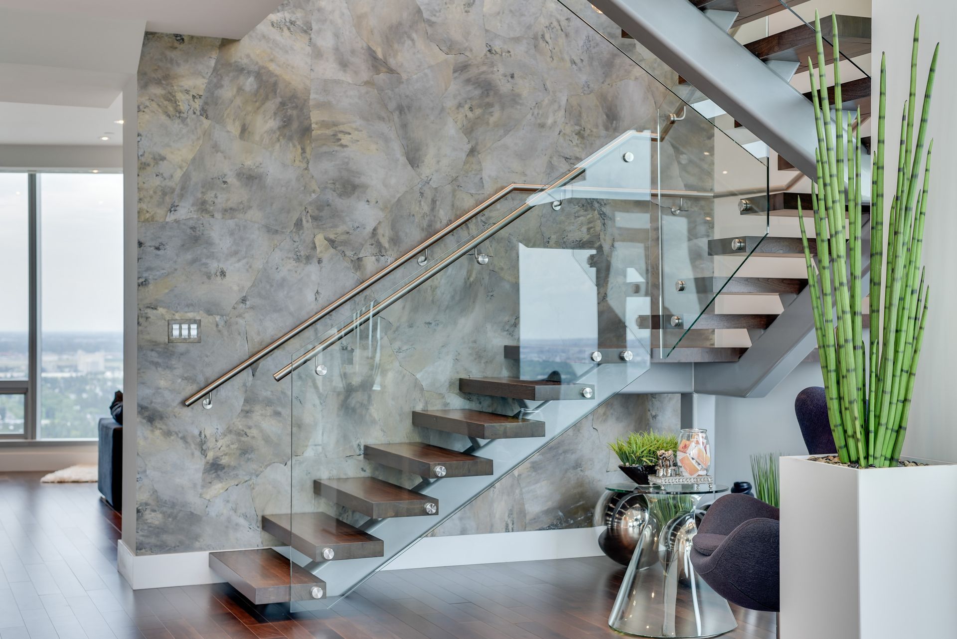 A modern staircase with a glass railing in a living room