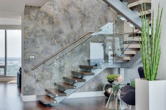 A modern staircase with a glass railing in a living room