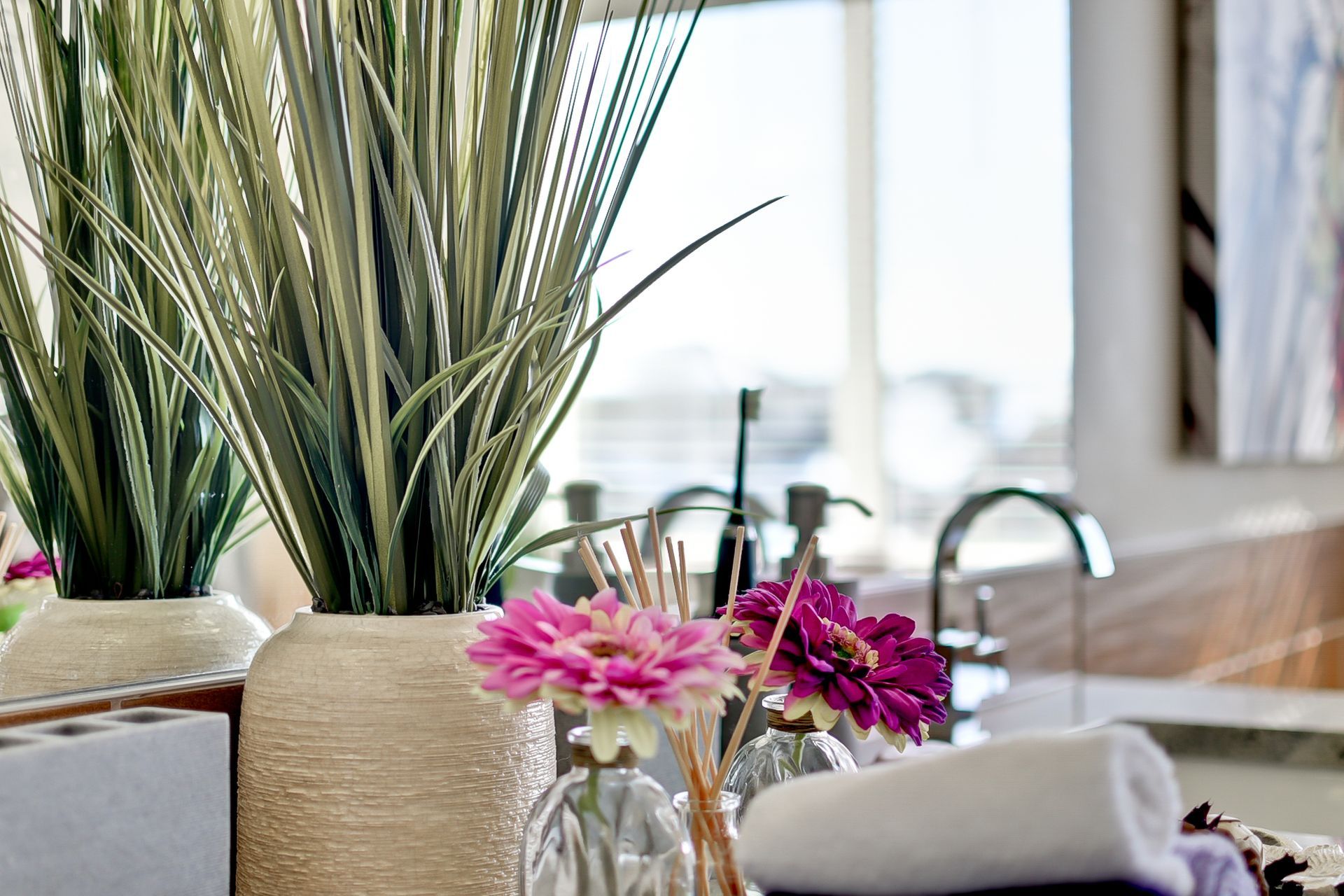 A vase filled with pink flowers is on a table in a kitchen.