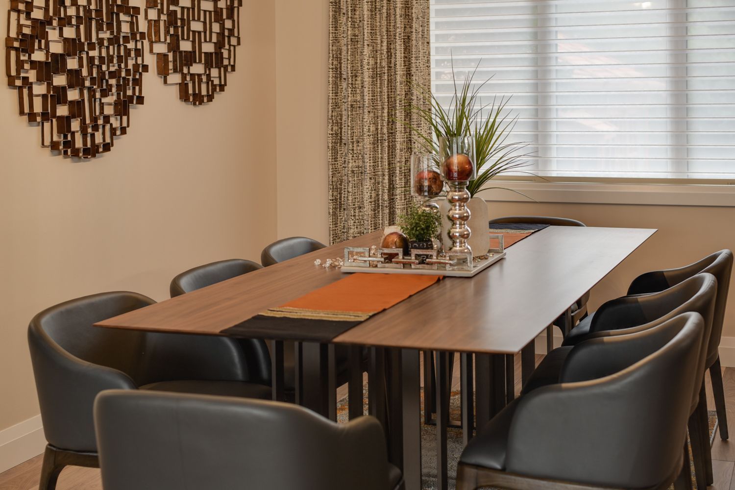 A dining room with a table and chairs in front of a window.