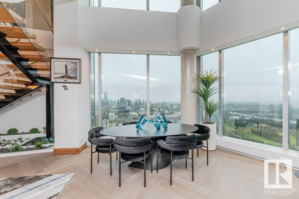 A dining room with a table and chairs in front of a large window.