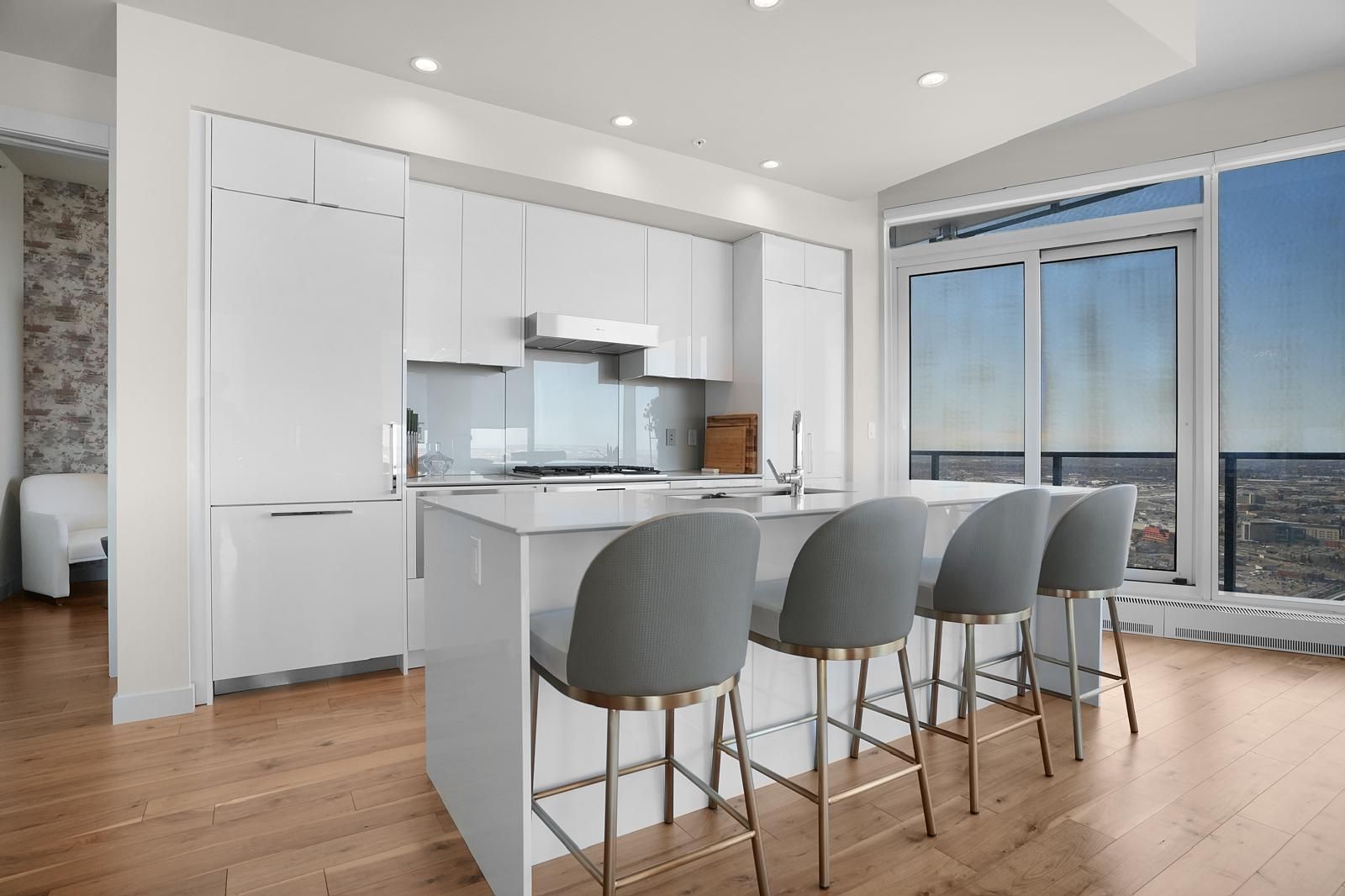 A kitchen with white cabinets and stools and a large island.