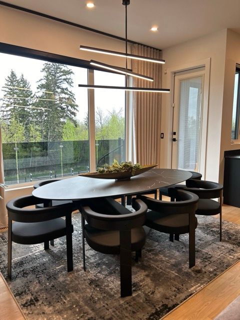 A dining room with a table and chairs and a large window
