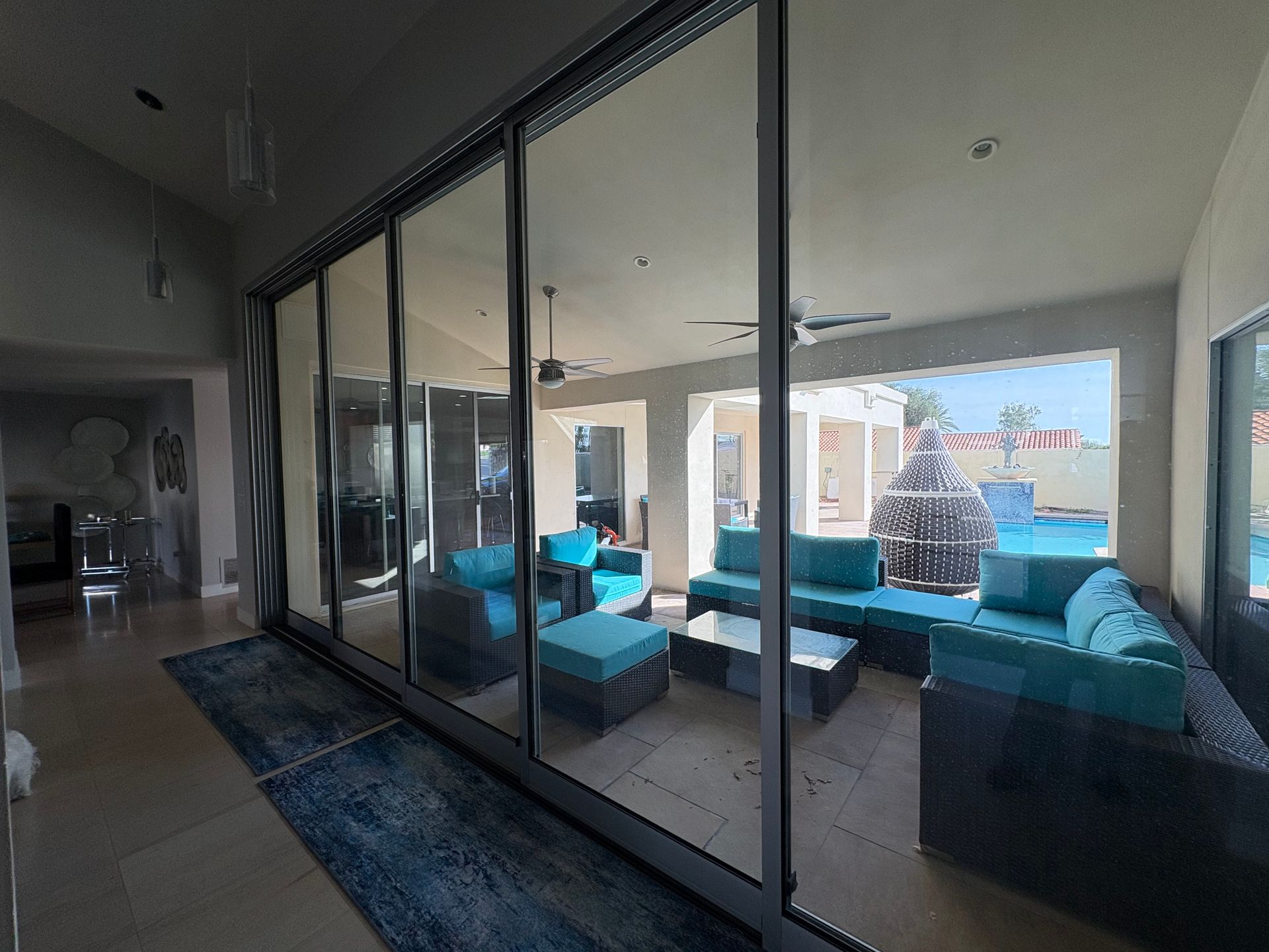 Patio with sliding glass doors, teal outdoor furniture, pool visible.