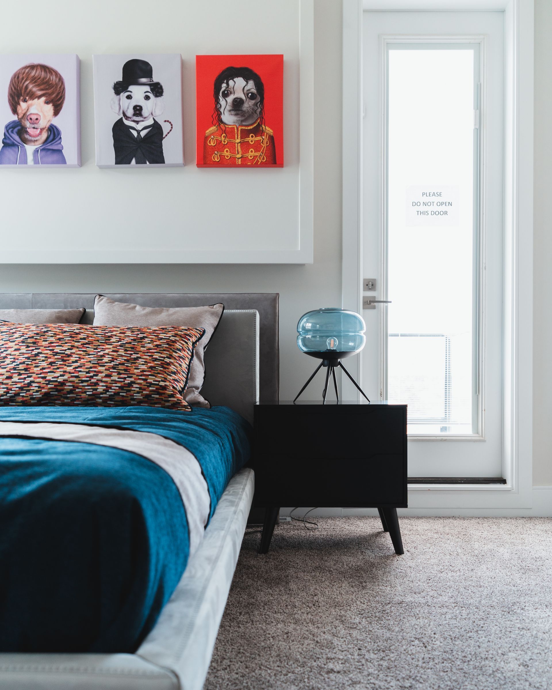 A bedroom with a bed , nightstand , and paintings on the wall.