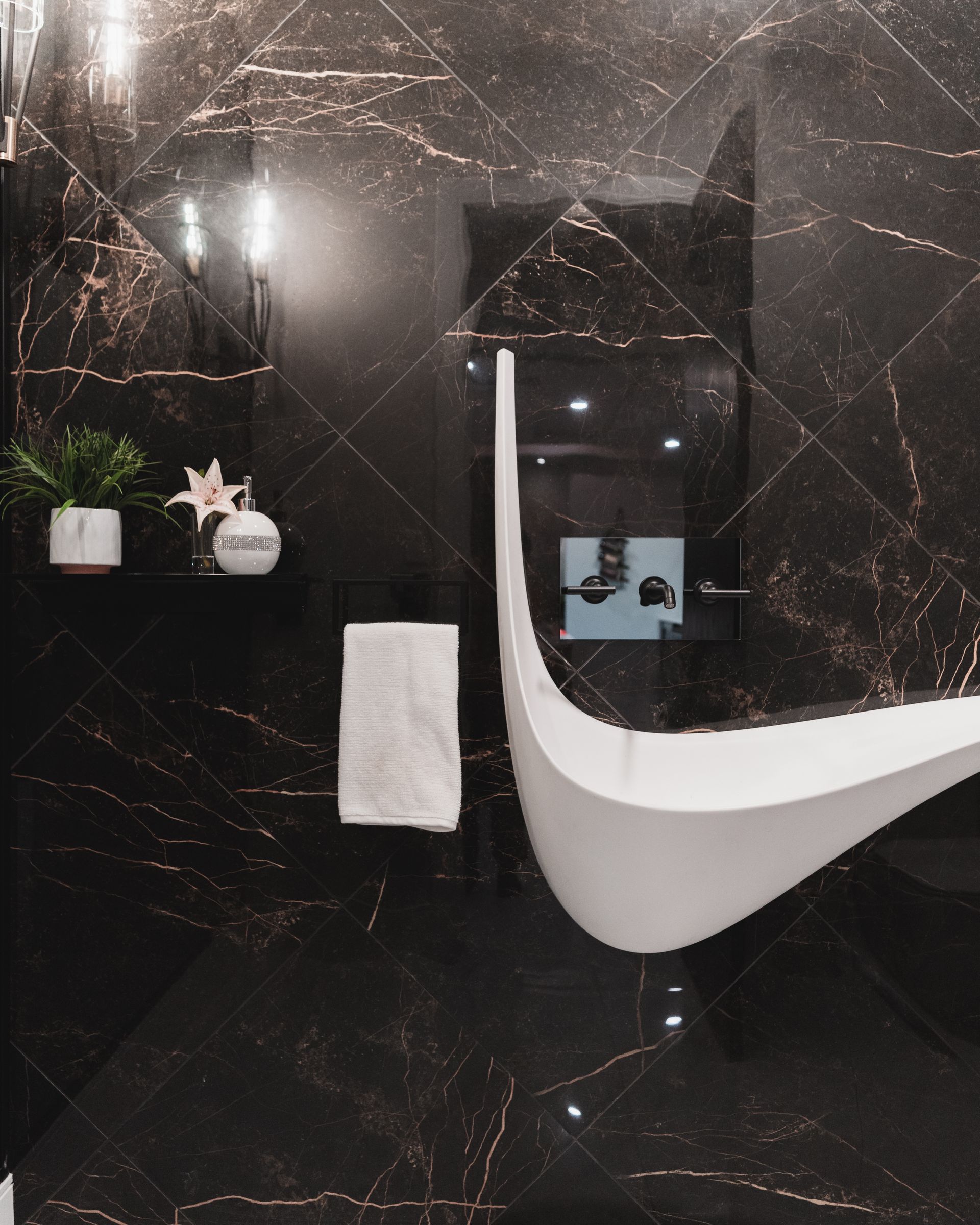 A bathroom with black tiles and a curved bathtub