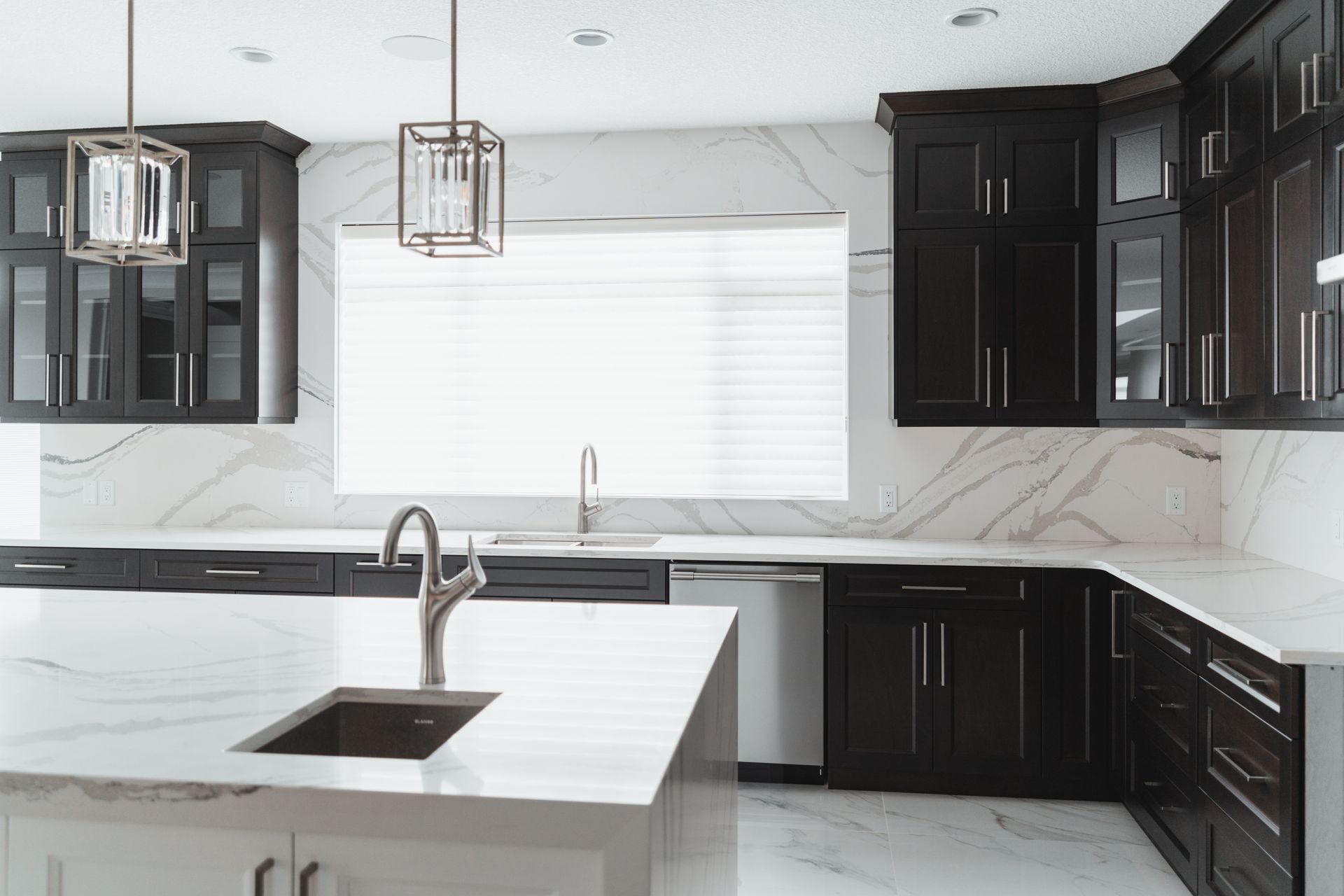 A kitchen with black cabinets and white counter tops and a sink.