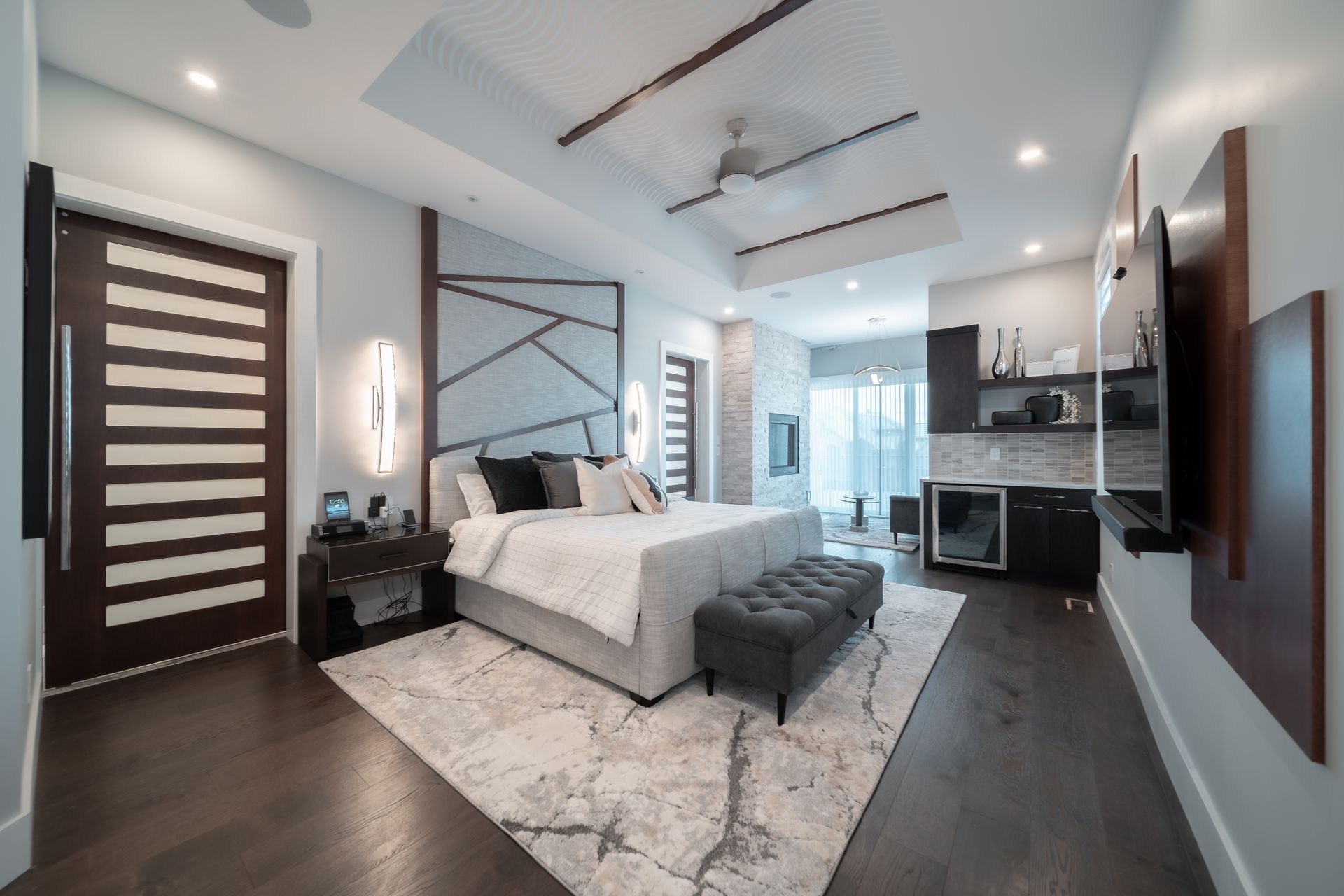 A bedroom with a large bed , a rug , a television and a ceiling fan.