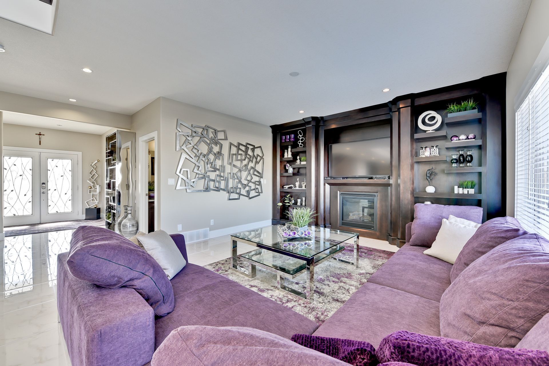 A living room with purple furniture and a fireplace.