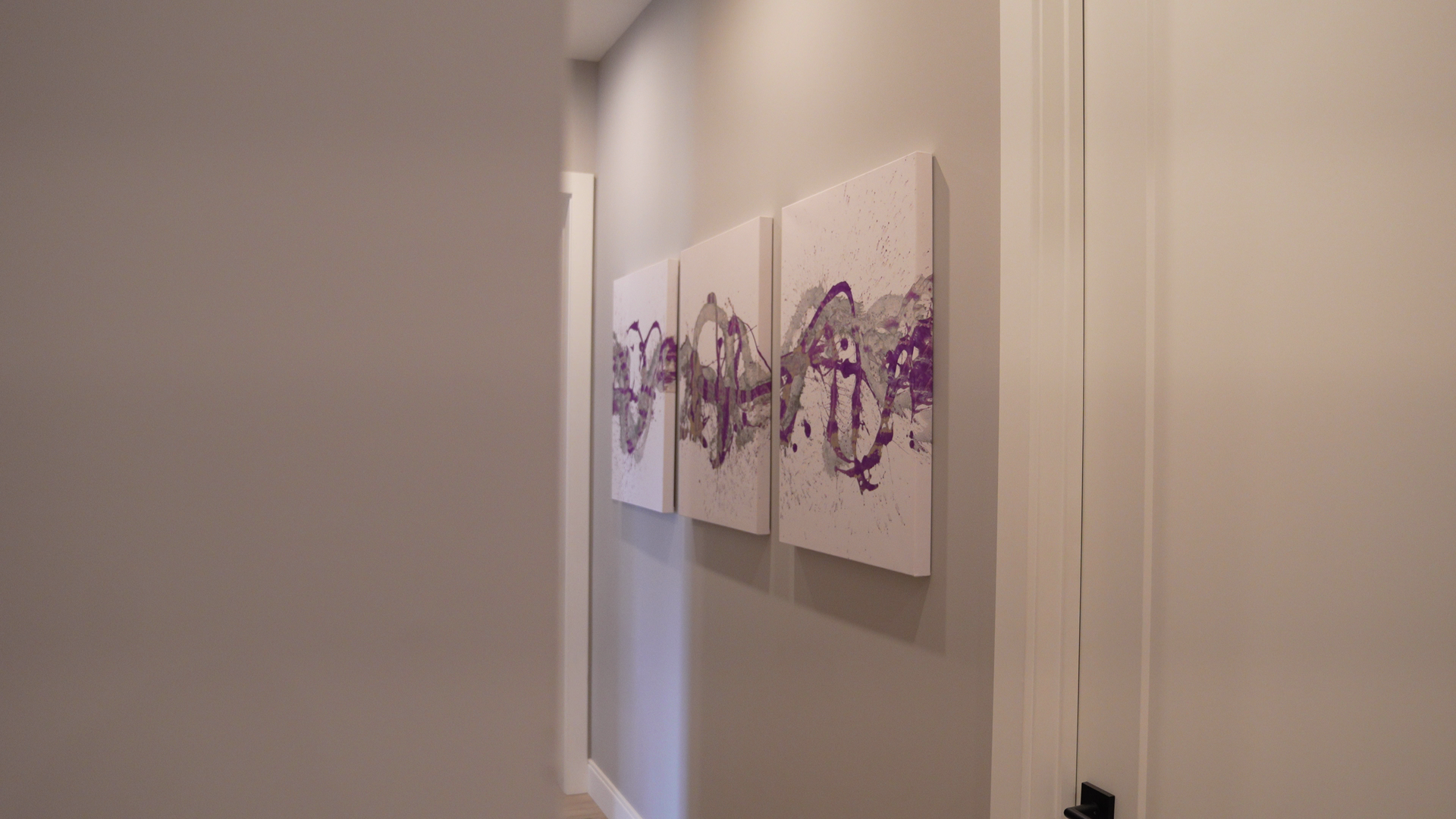 A hallway with three paintings on the wall.