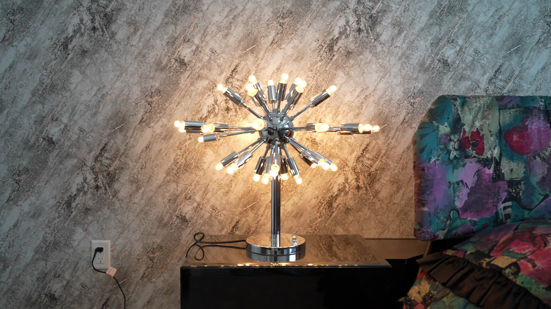 A table lamp is sitting on a nightstand next to a bed.