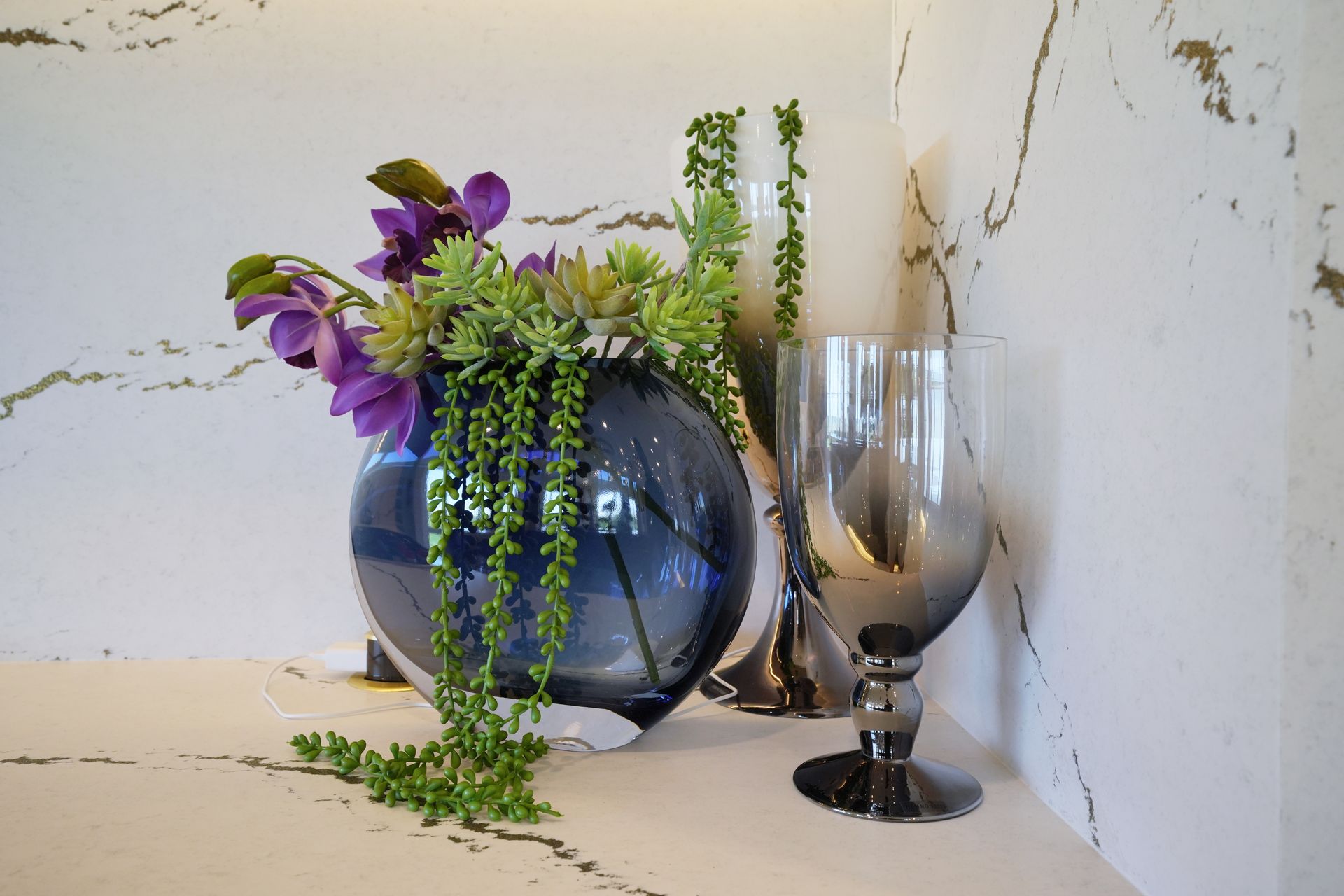 A vase filled with flowers and a wine glass on a table.
