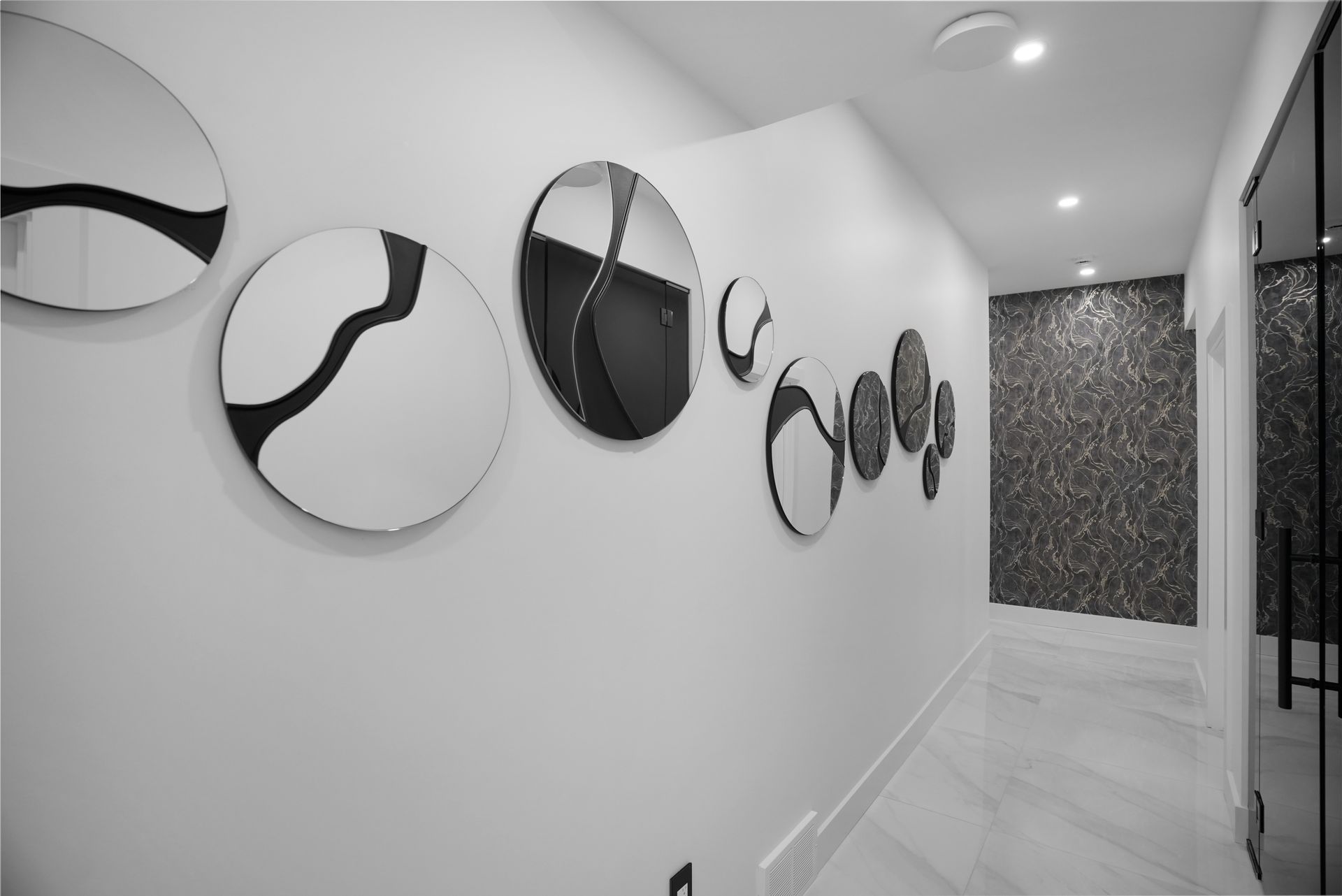 A black and white photo of a hallway with mirrors on the wall