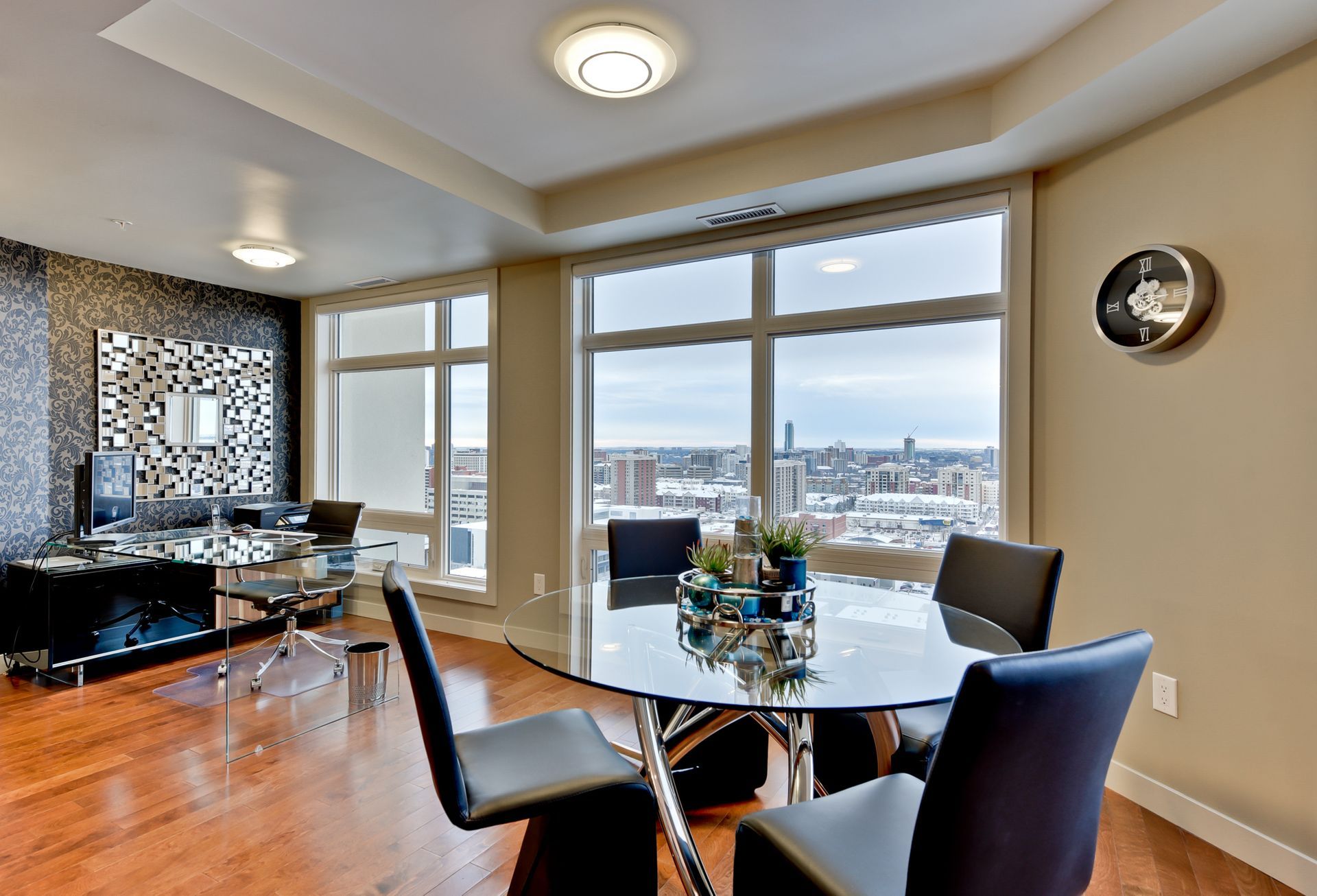 A dining room with a glass table and black chairs