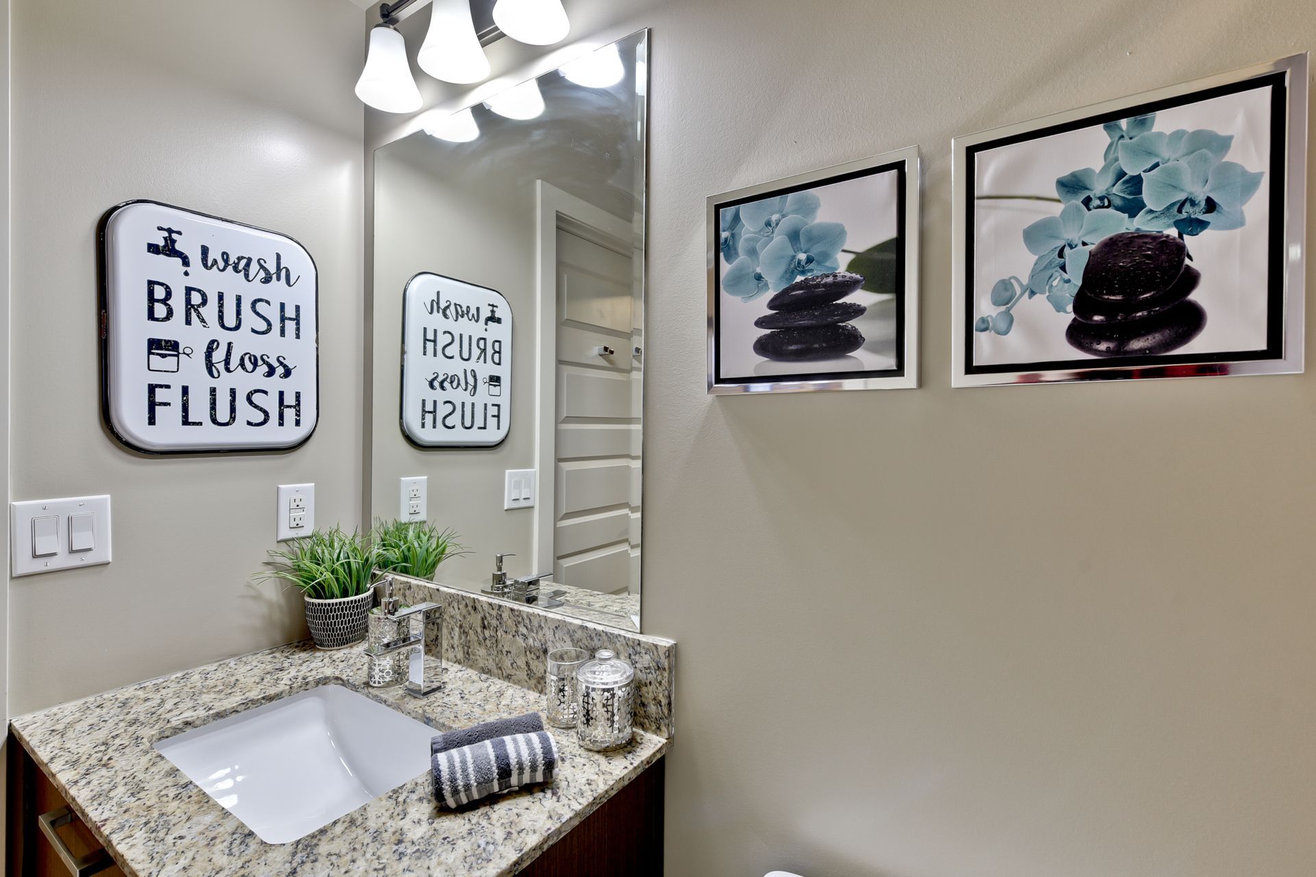 A bathroom with a sink , mirror , and pictures on the wall.