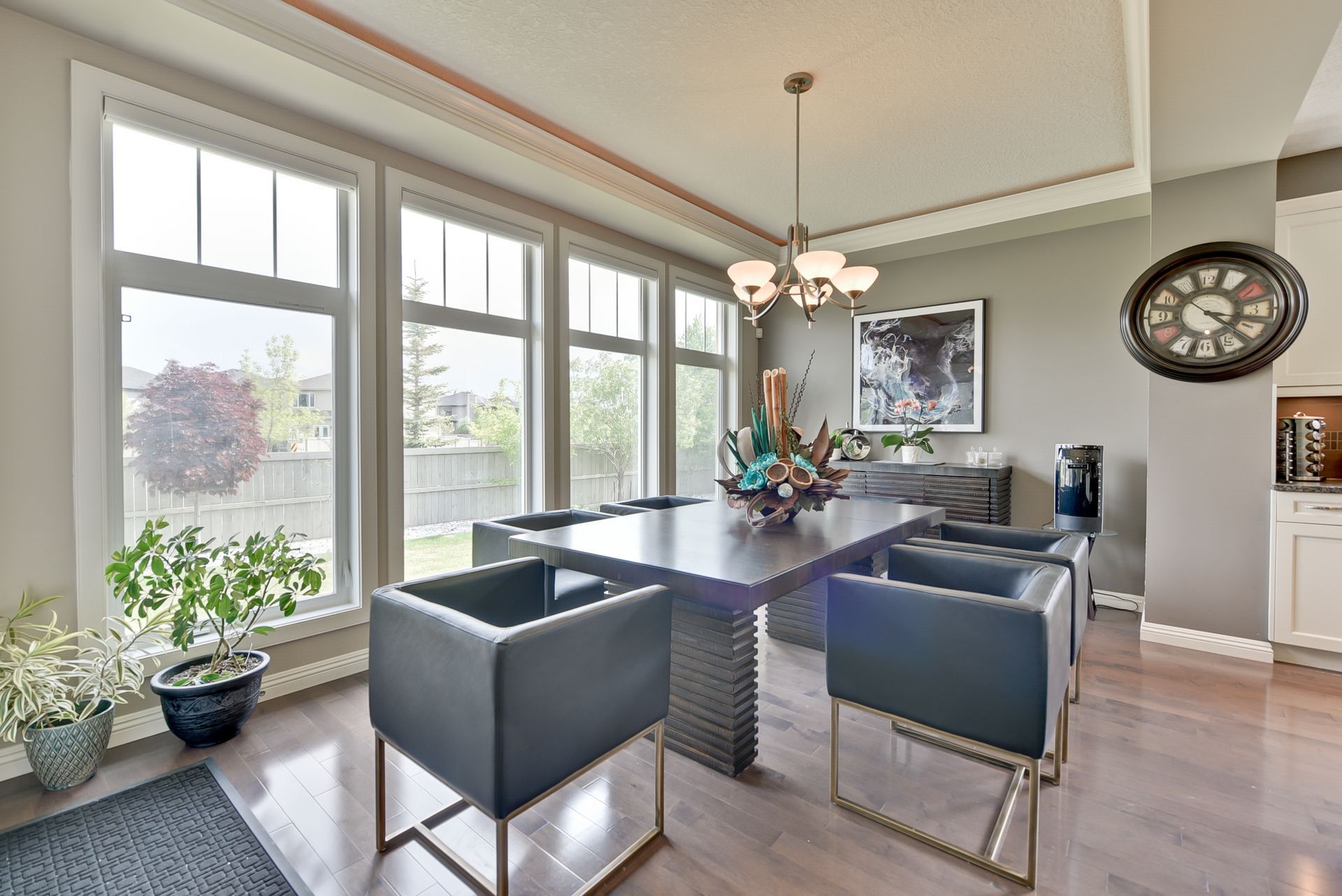 A dining room with a table and chairs and a clock on the wall.