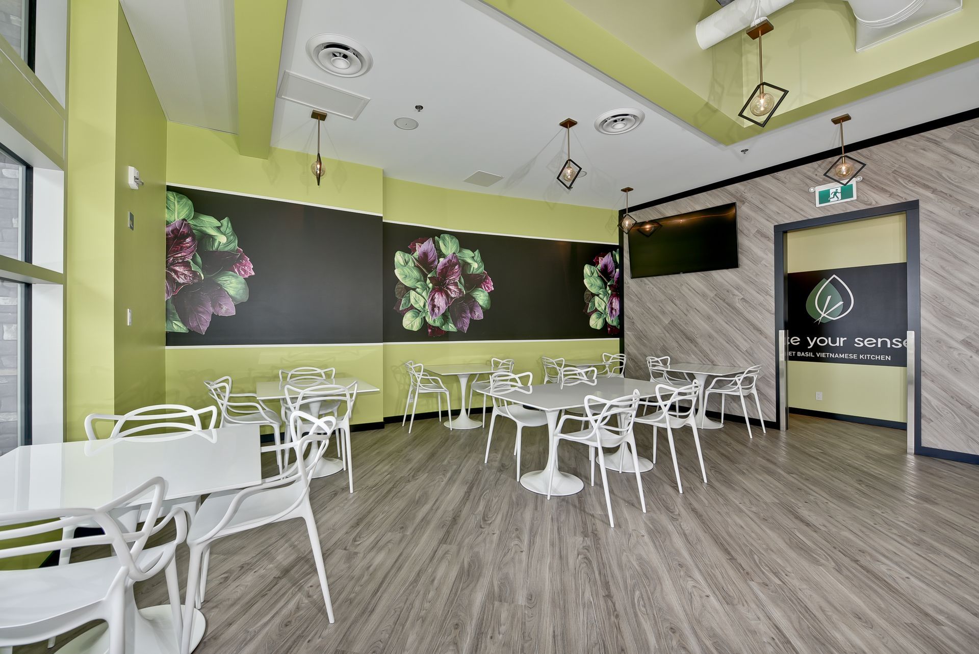 A dining room with tables and chairs and a chalkboard on the wall.